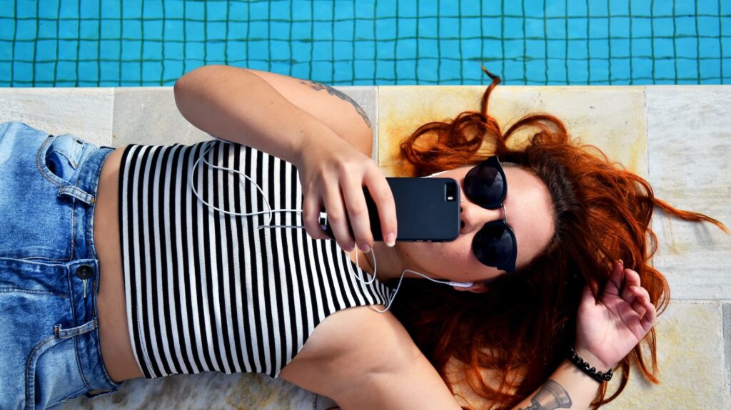 Girl watching video on phone near pool